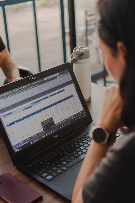 Solopreneur reviewing a Genspark AI Workspace spreadsheet output in a cafe
